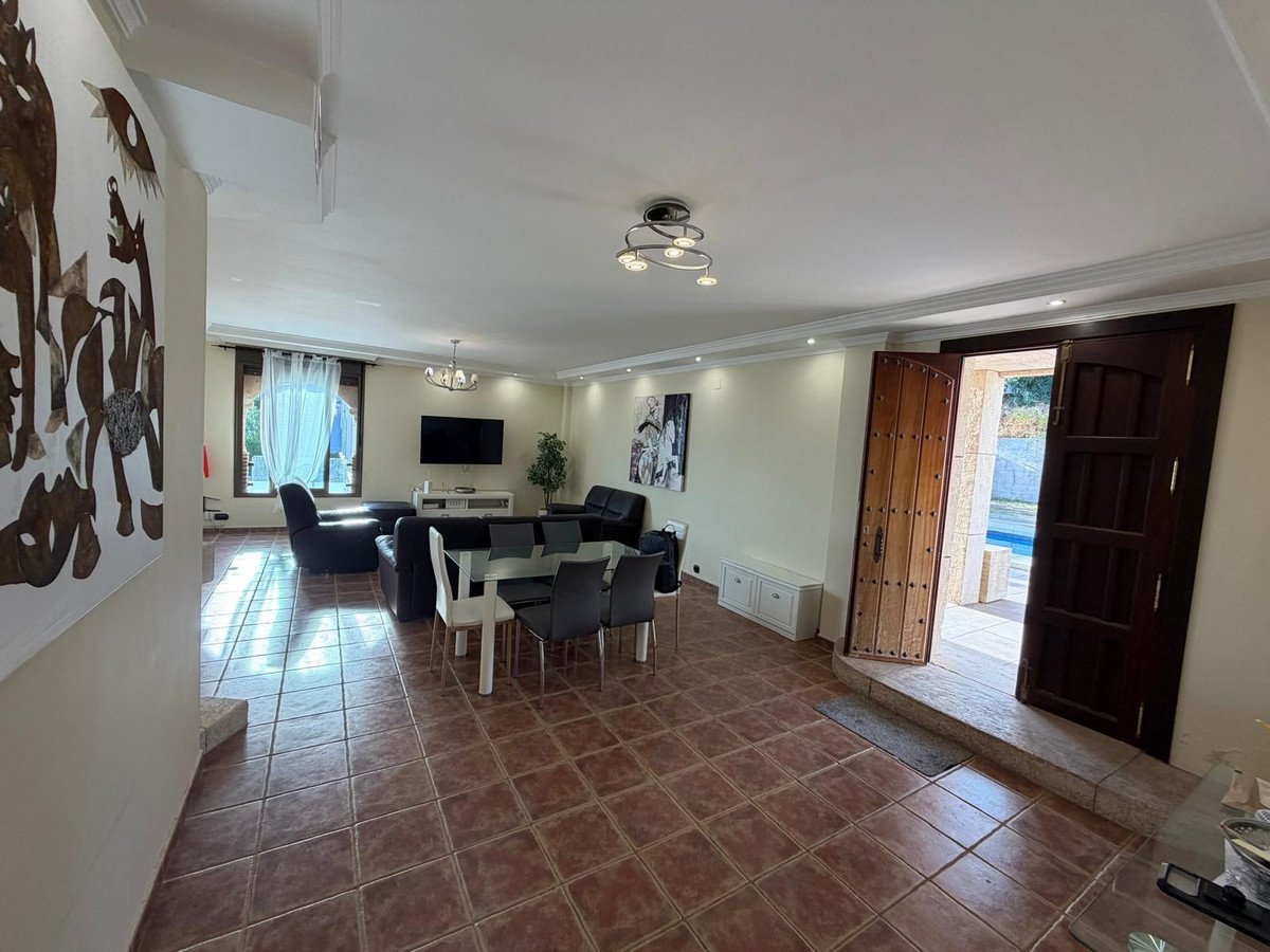 Spacious living and dining area with a modern dining table, comfortable seating, and direct access to a swimming pool area.