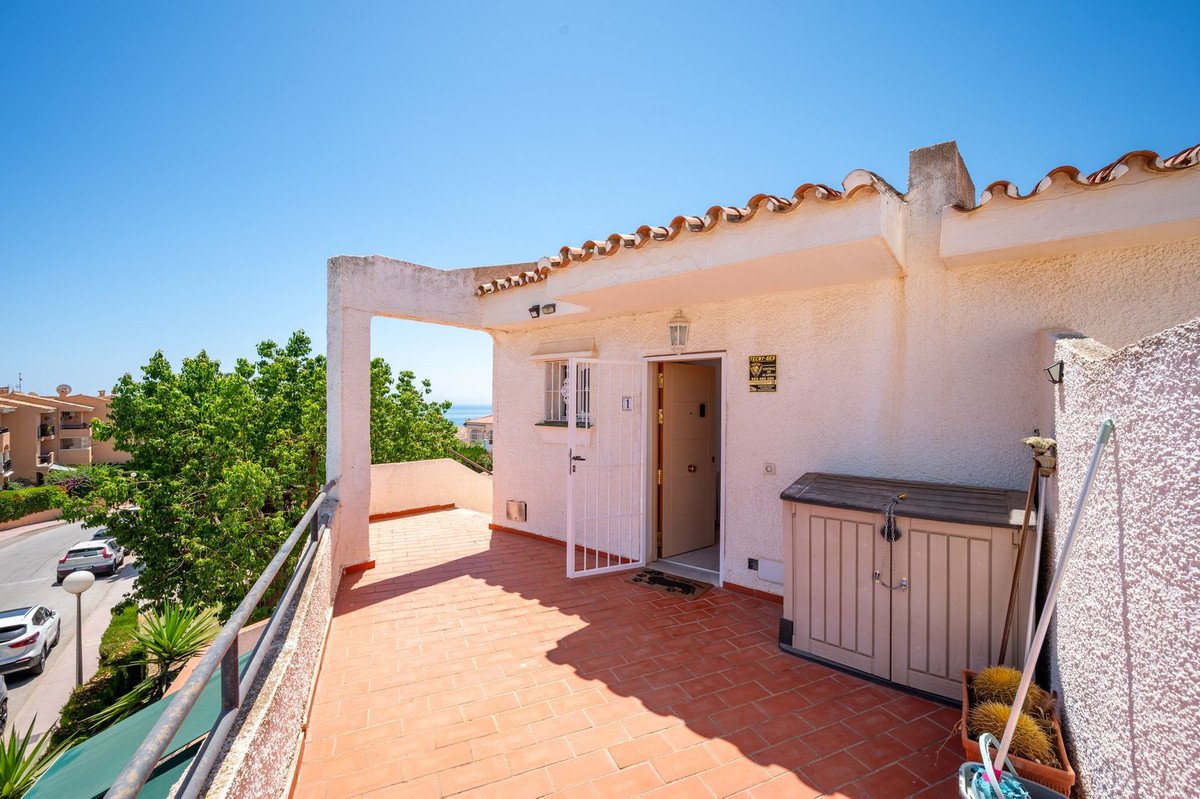 Terrace with sea and green tree views, featuring terracotta tiles and an outdoor storage box.