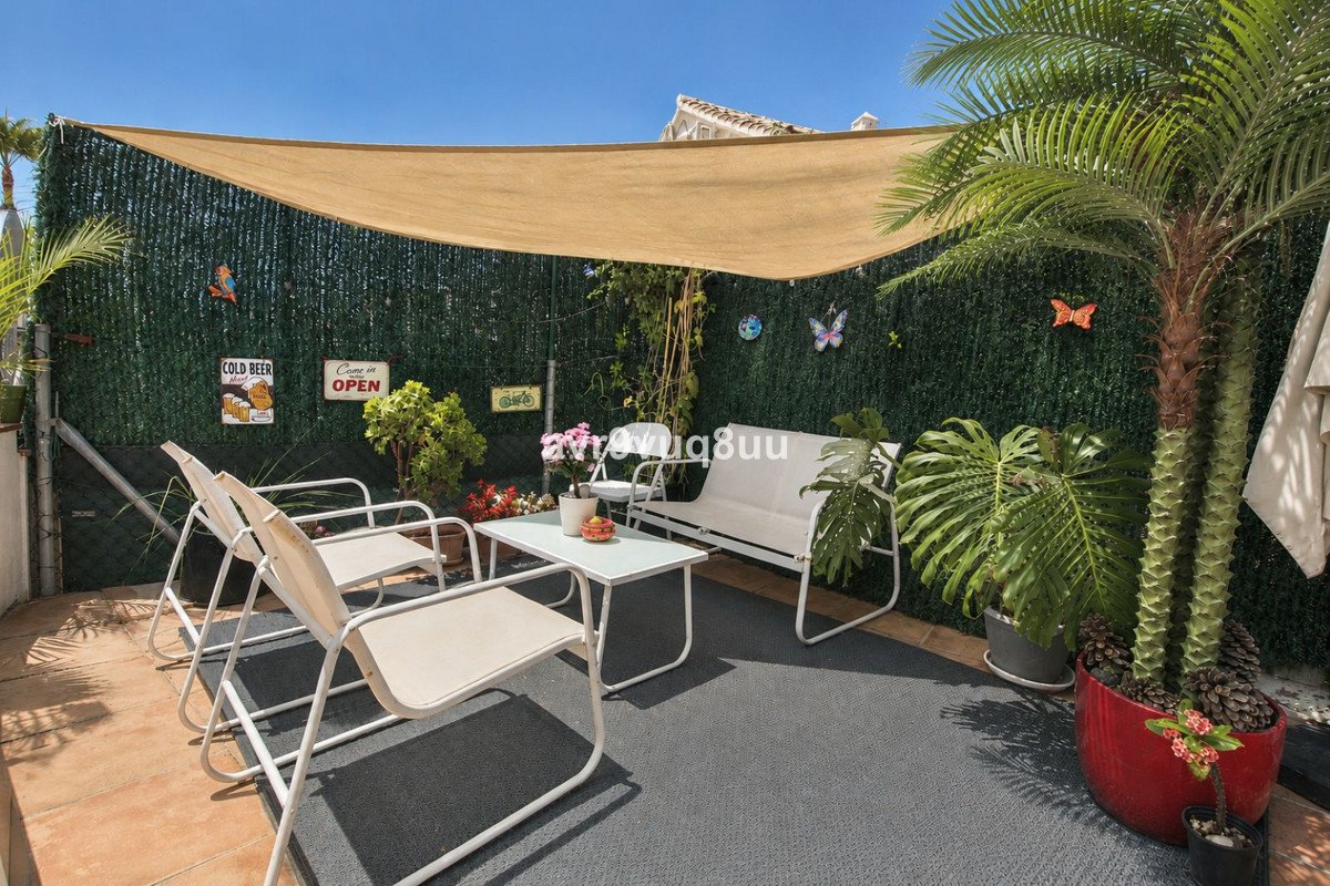 Outdoor terrace seating area with white furniture, plants, and a sunshade, decorated with vintage signs and butterflies.