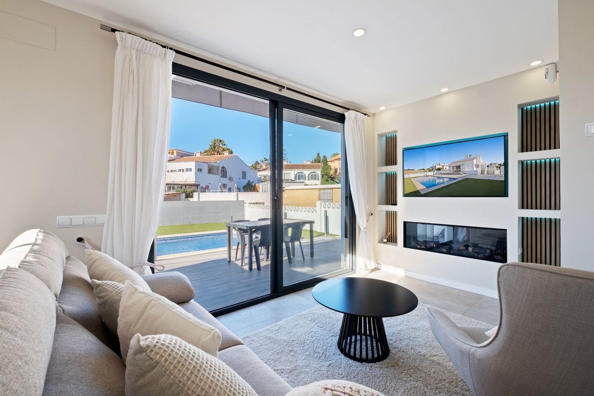 Modern living room with a comfortable sofa, a sleek fireplace, and a large window overlooking a private pool and patio area.