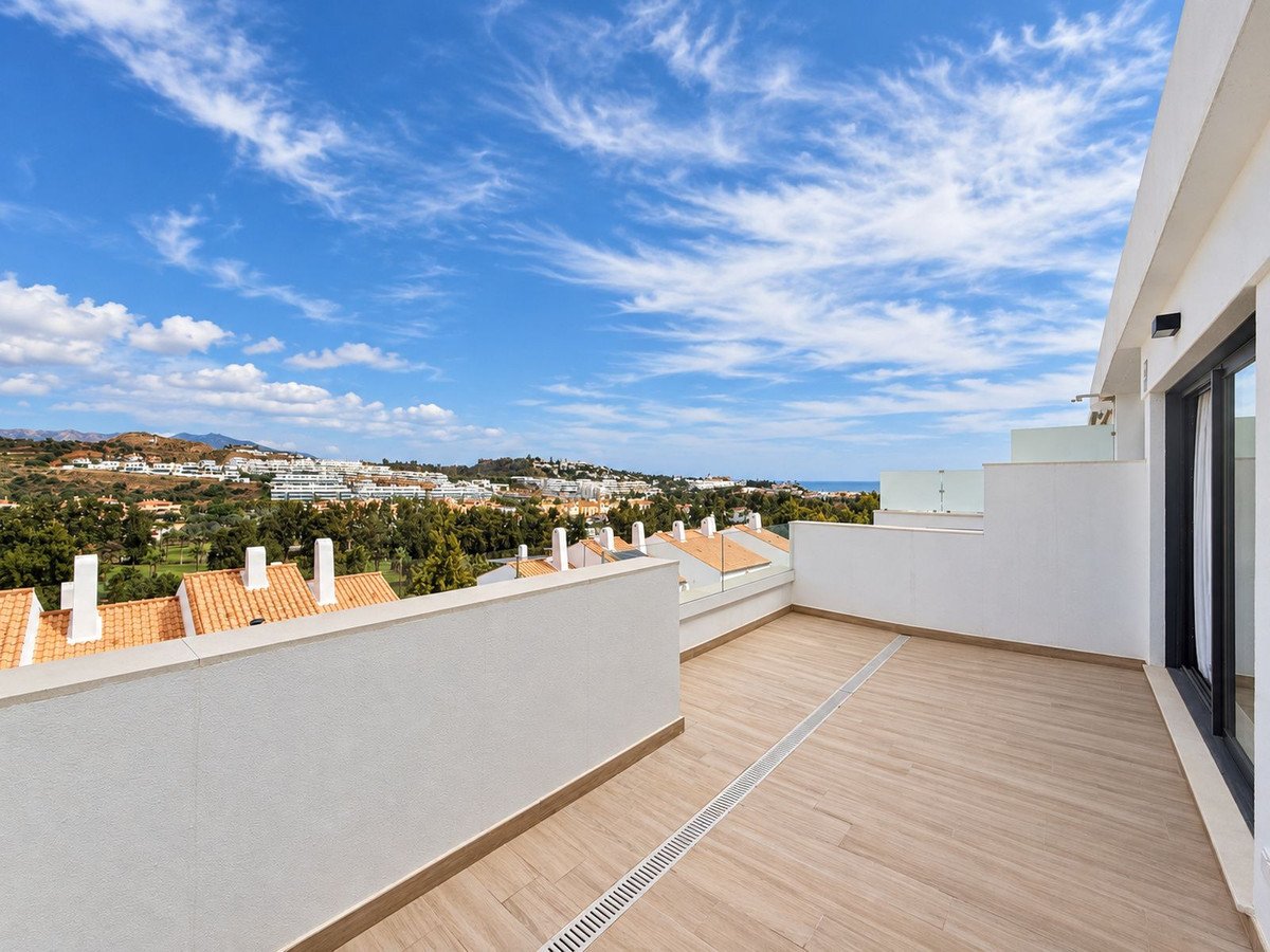 Spacious modern terrace with a sea and golf course view, featuring wooden flooring and glass balustrades.