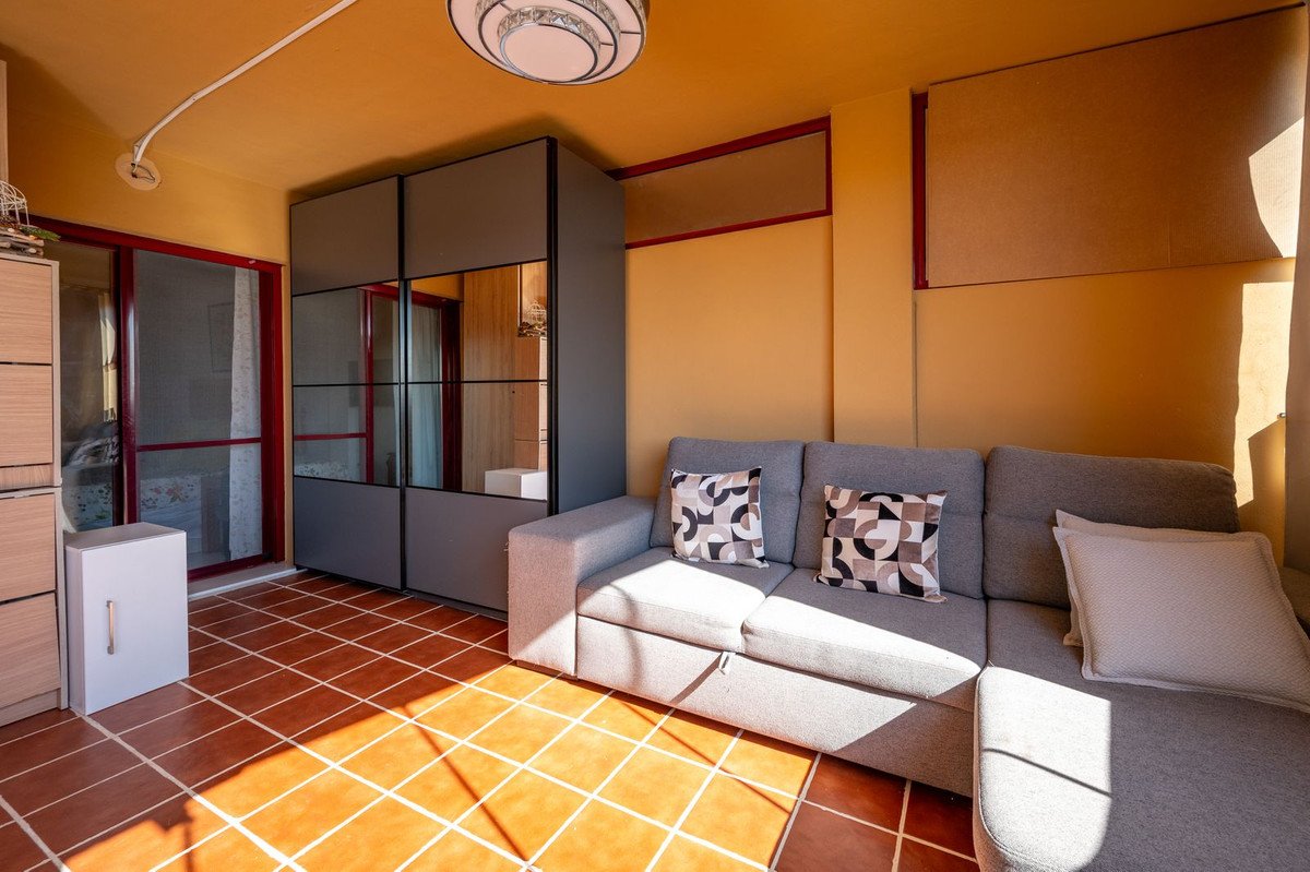 Sunny living room with grey sofa, mirrored wardrobe, and outdoor terrace view