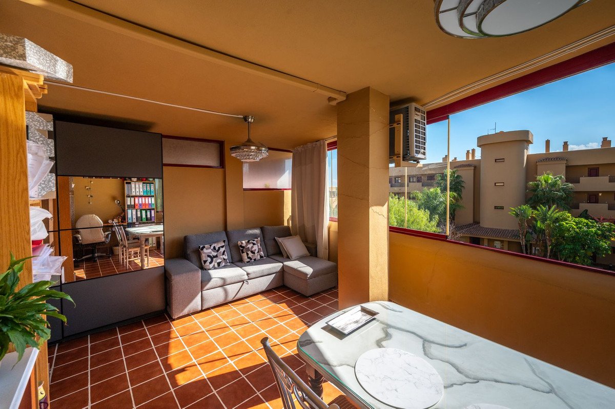 Balcony with sofa, dining table, and view of surrounding buildings and greenery