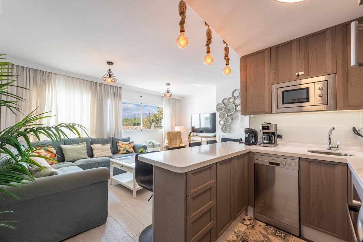 Modern living room and kitchen area with a comfortable sofa, island, and view from the balcony.