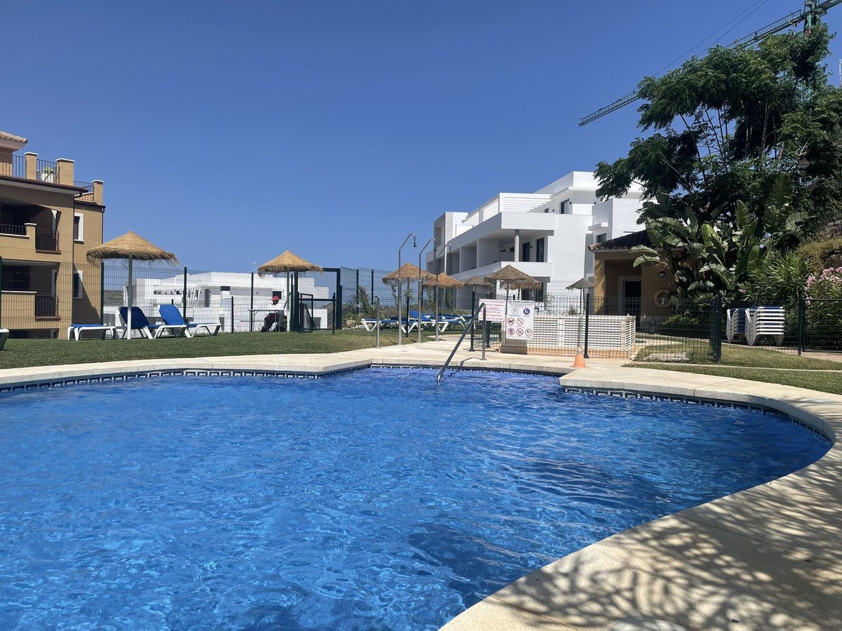 Resort swimming pool with sun loungers and white buildings in background