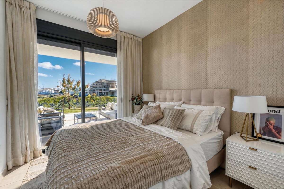 A luxurious bedroom with a king-size bed, textured wallpaper, and a sliding glass door leading to a balcony with sea views.