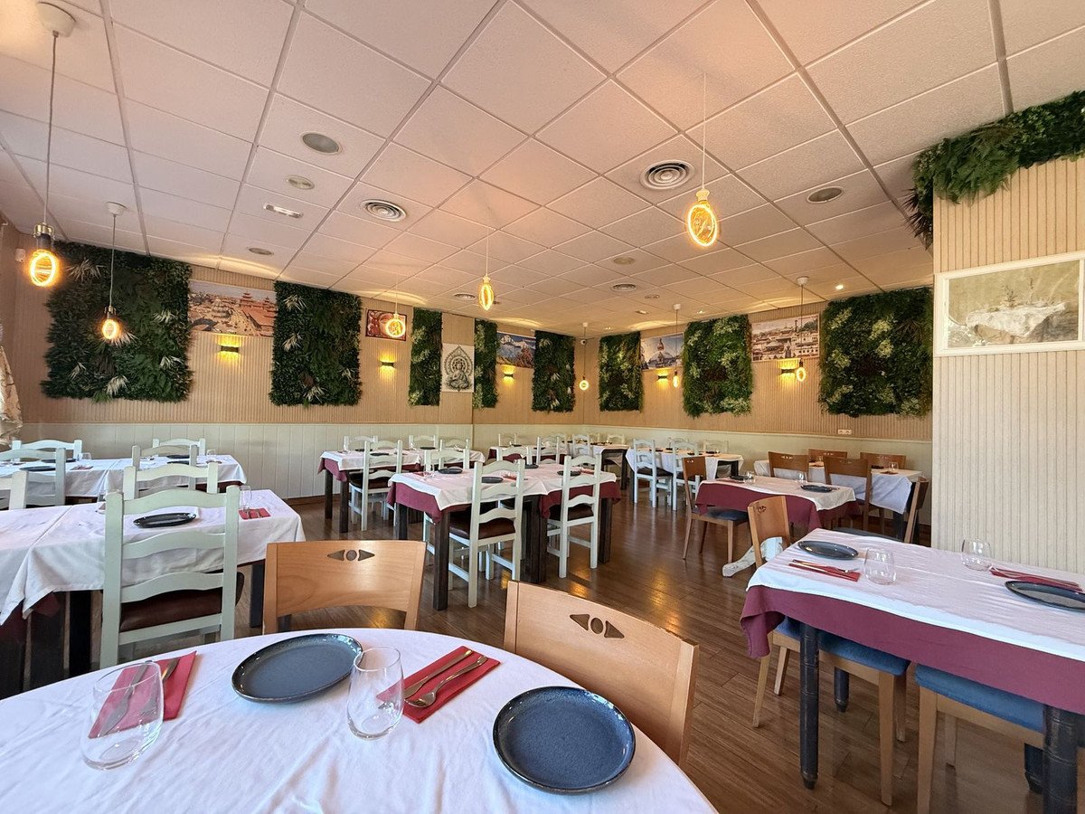 Restaurant dining room with white tablecloths, chairs, and decorative vertical gardens on the walls.