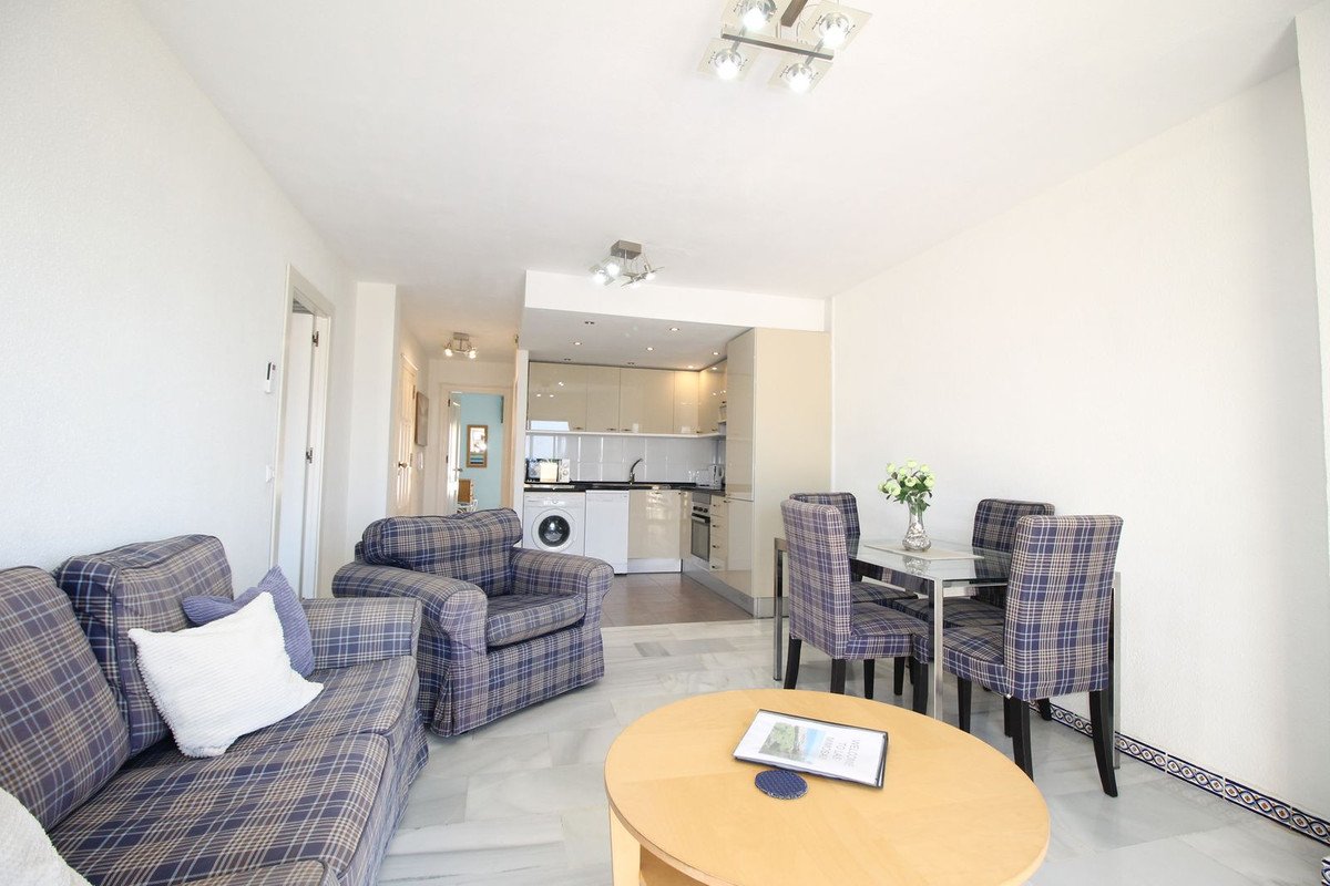 Open-plan living, dining, and kitchen area with plaid furniture and modern appliances