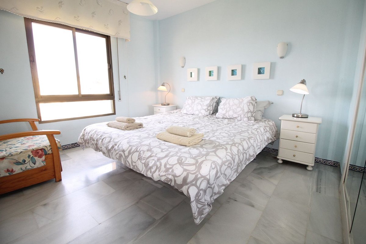 Bright bedroom with a large window, double bed, and white furniture