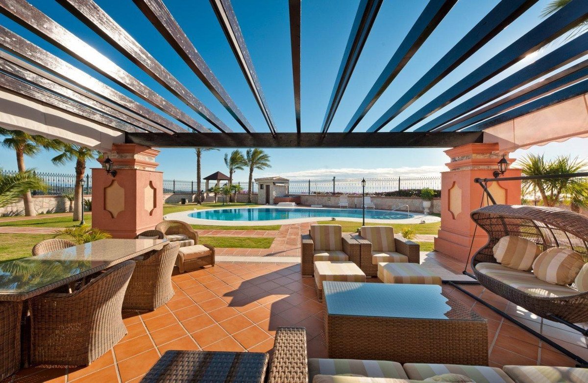 Outdoor patio with wicker furniture, pergola, and pool overlooking the sea