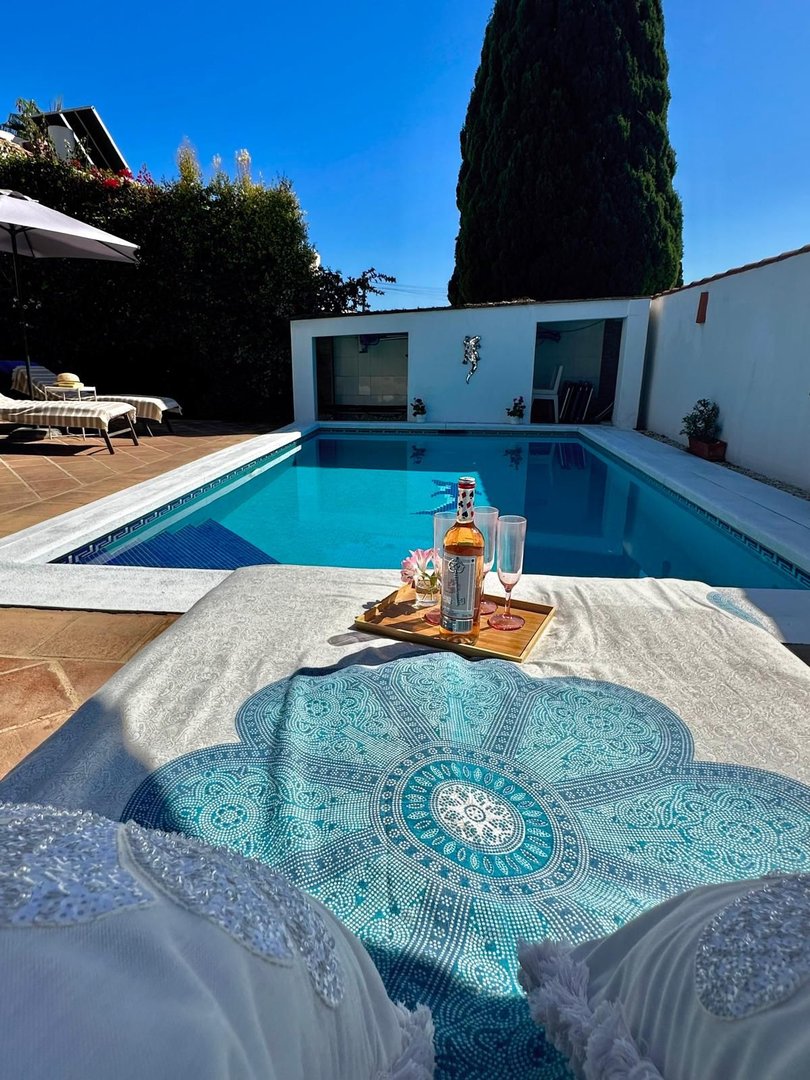 Outdoor pool with lounge sunbed, drinks, and sunny view
