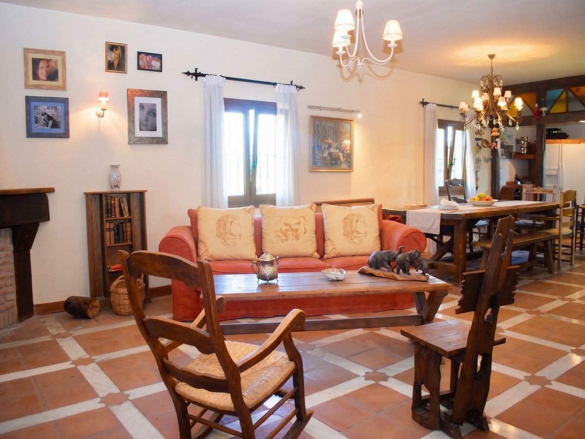 Spacious living and dining area with a fireplace, comfortable sofa, wooden furniture, and elegant chandeliers.