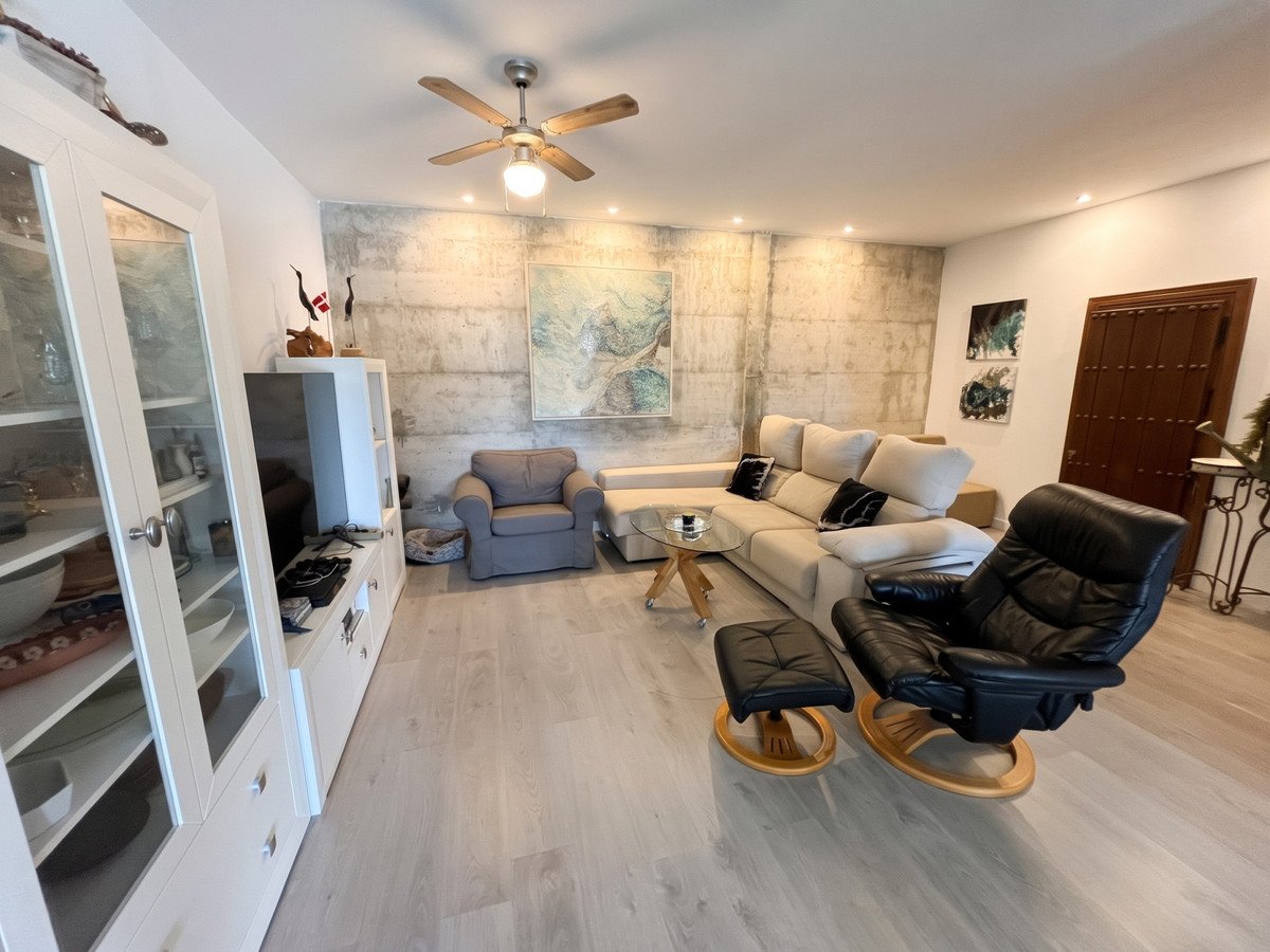 Spacious living room with modern furniture, light wood floors, and a ceiling fan.