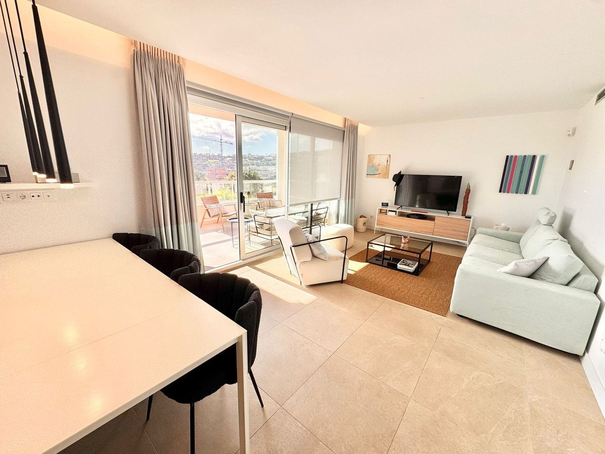 Modern living room with city view, dining table, sofa, and sliding glass doors