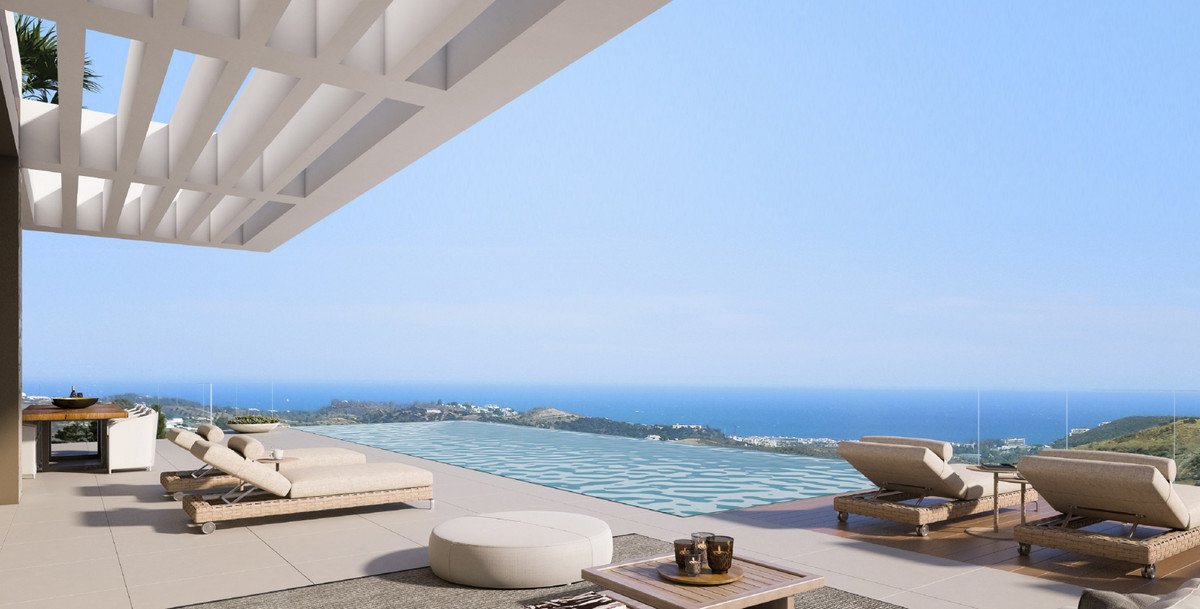 Modern terrace with infinity pool, lounge chairs, and a stunning ocean view during the day.