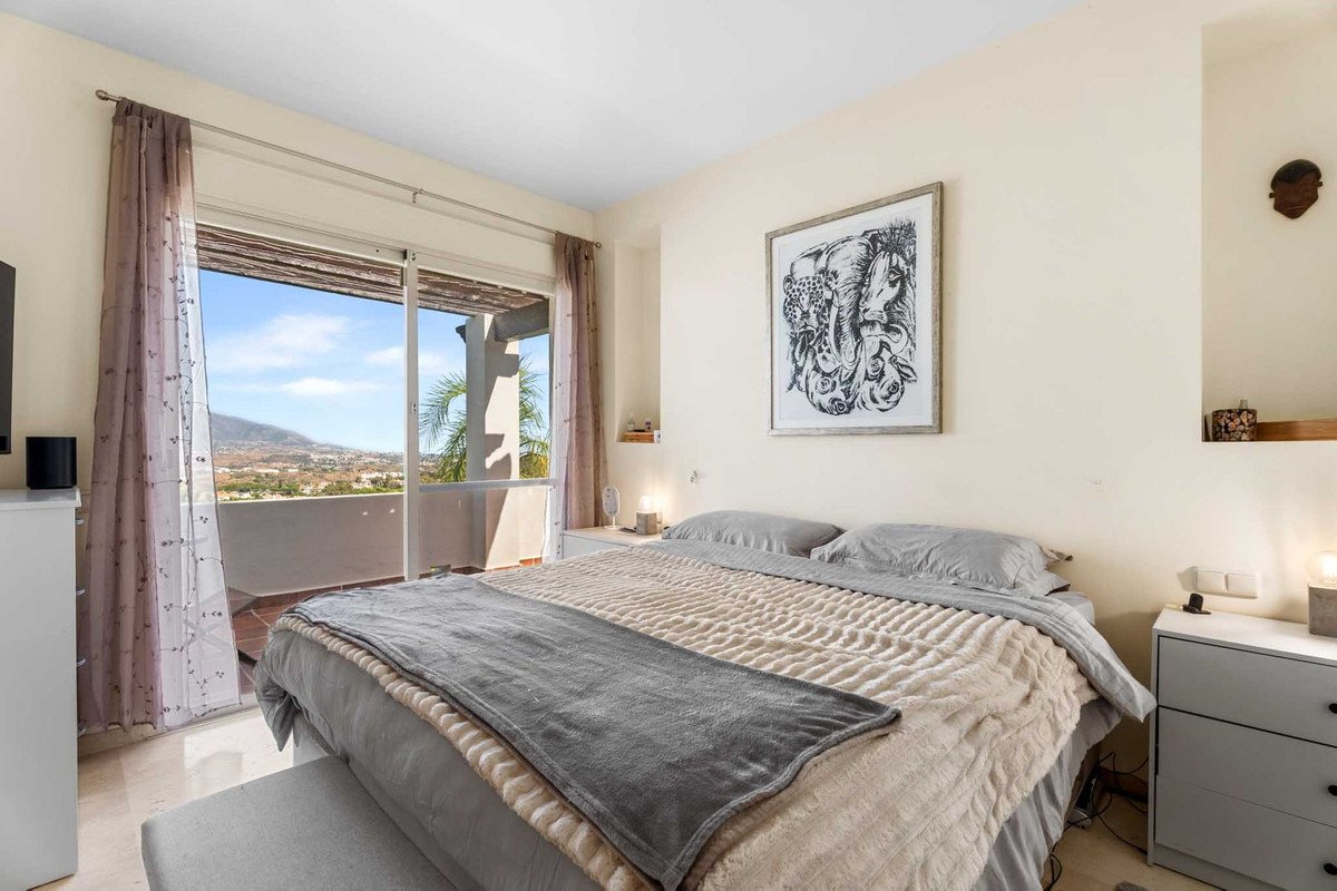 A bedroom with a large bed, a balcony door offering a mountain view, and framed elephant artwork on the wall.