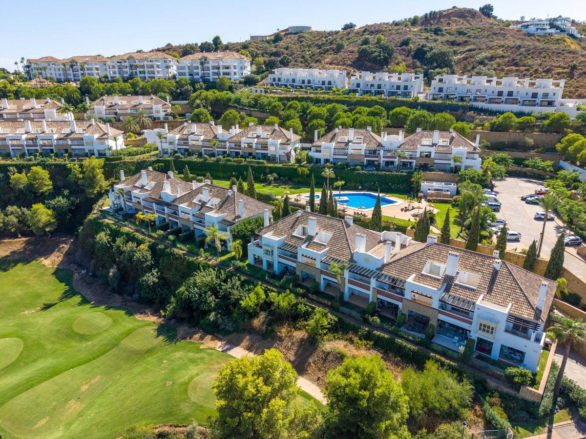 Luxury villas with a swimming pool and golf course view, set on a hillside with lush greenery and distant mountains.