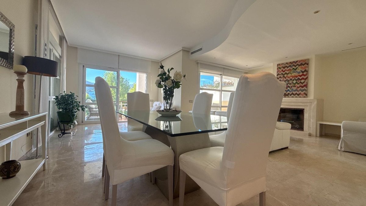 Modern dining and living room with sea view, fireplace, and large windows