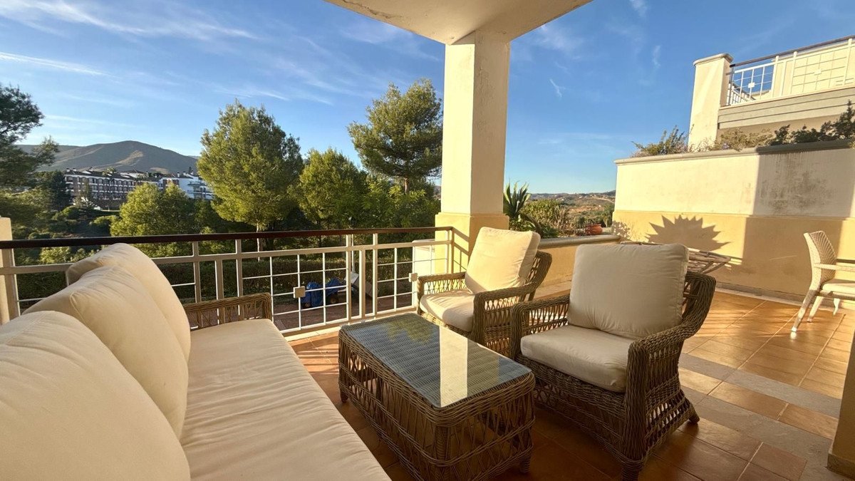 Balcony with wicker seating, cushions, and mountain view
