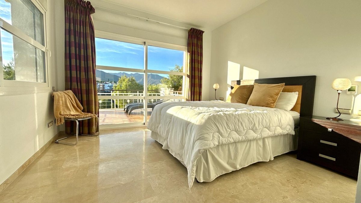 Spacious bedroom with large bed, sliding doors to balcony, mountain view