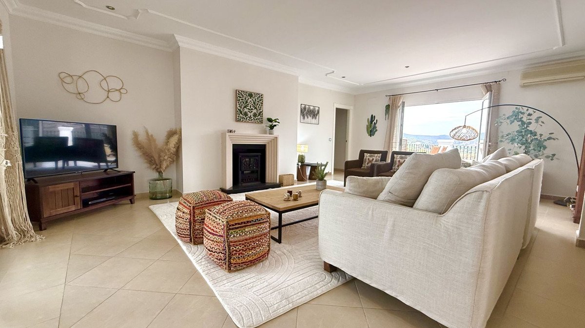 Bright living room with fireplace, comfortable sofa, and a stunning view of the ocean through large open doors.