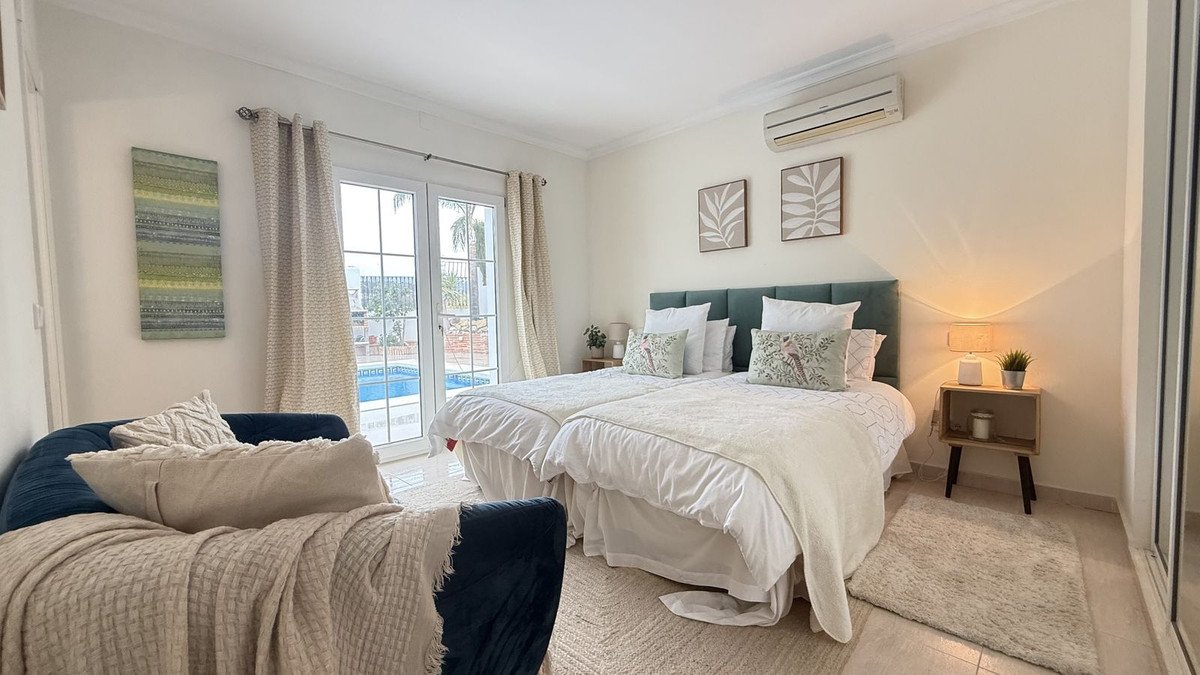 A bedroom with two twin beds, teal headboard, and French doors opening to a pool area.