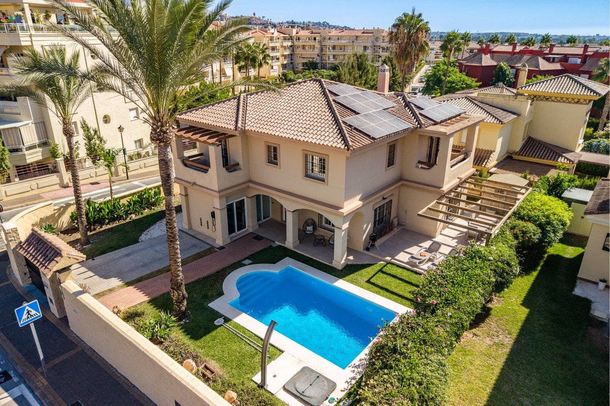 Modern villa with a private swimming pool, solar panels on the roof, and lush garden surrounded by palm trees.