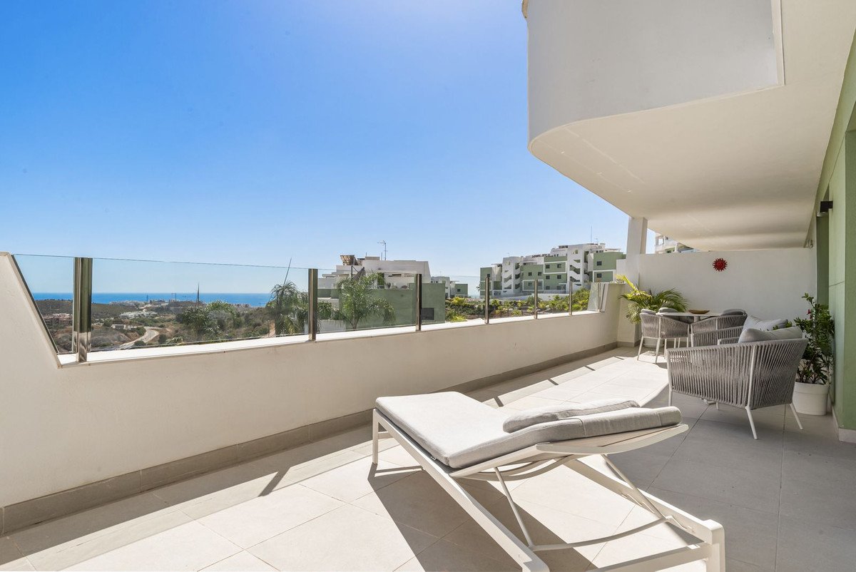 Spacious modern terrace with lounge furniture and a chaise lounge, offering distant sea and urban views.