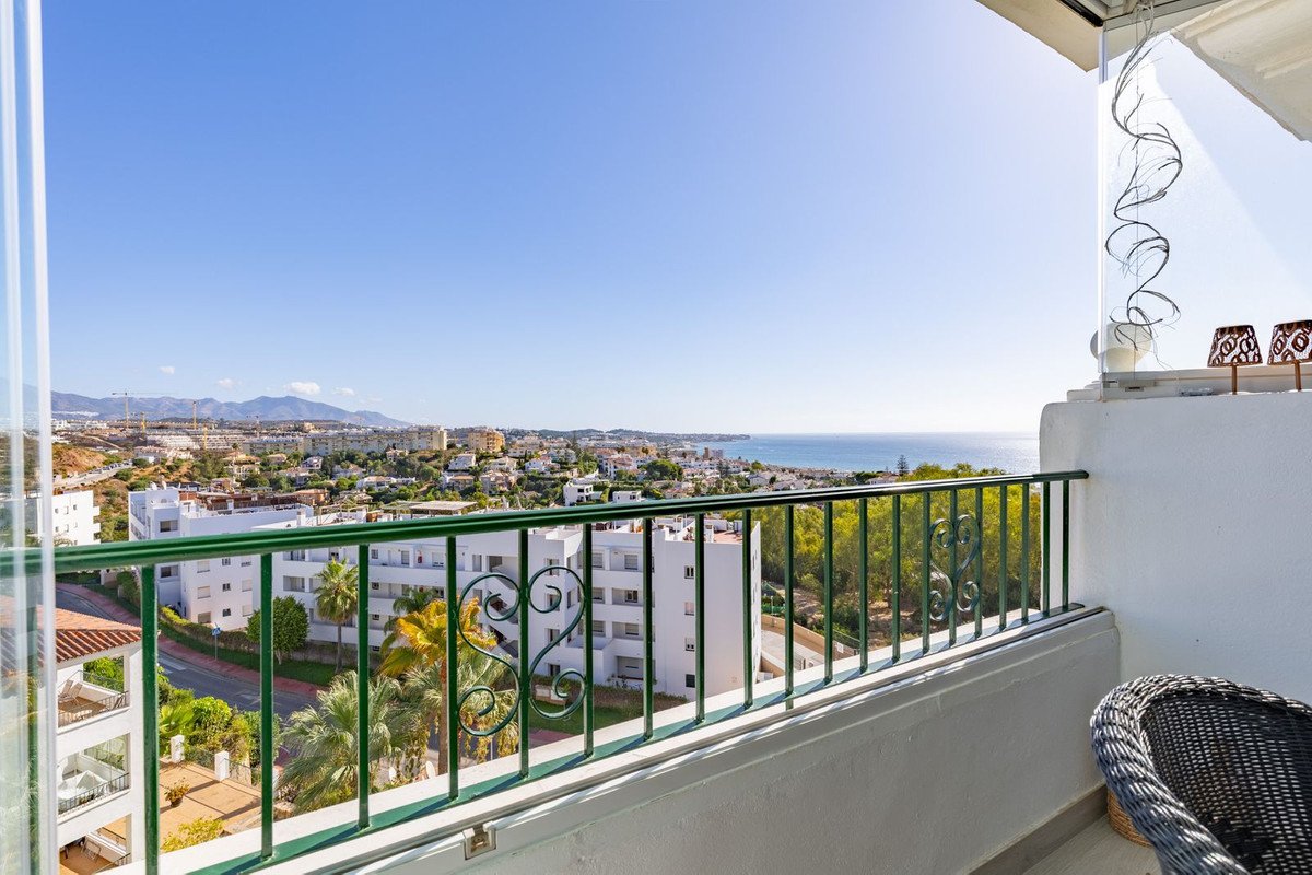 Balcony view of a coastal town and the sea on a sunny day. Features intricate railing.
