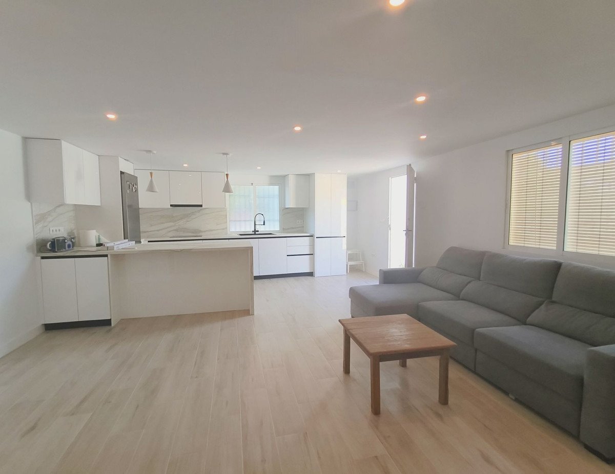 Spacious open-plan living area with a modern kitchen, grey sectional sofa, and a wooden coffee table.