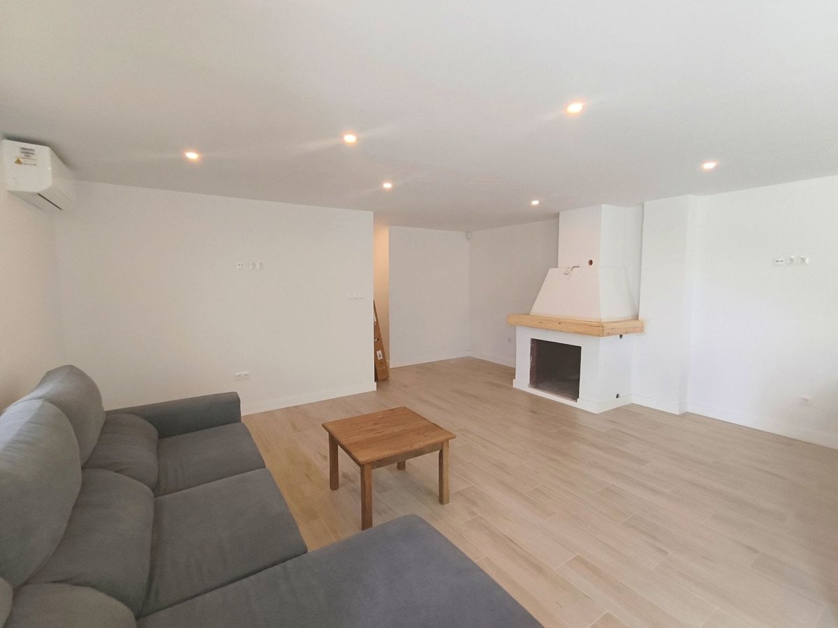 Spacious living room with a grey sectional sofa, wooden coffee table, and a white fireplace with a wooden mantelpiece.