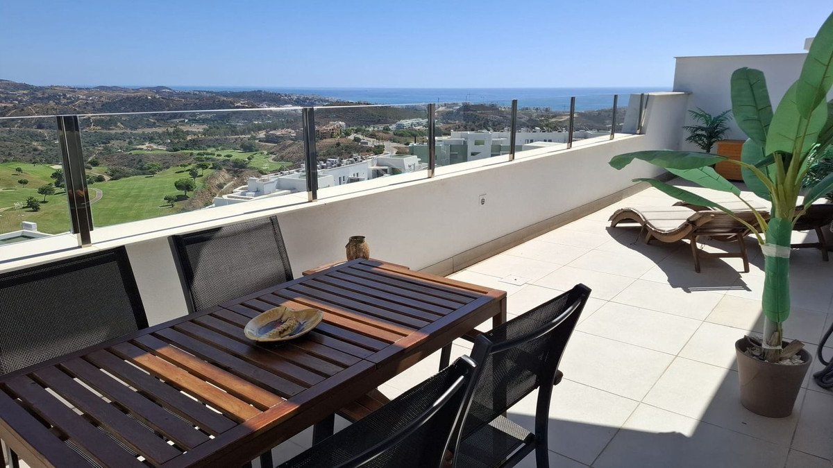 Spacious terrace with dining table, lounge chairs, and a panoramic view of the sea and golf course.