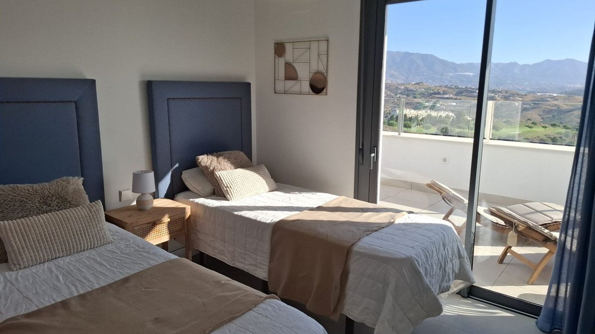 Bedroom with two single beds, modern decor, and a balcony with stunning mountain and landscape views.