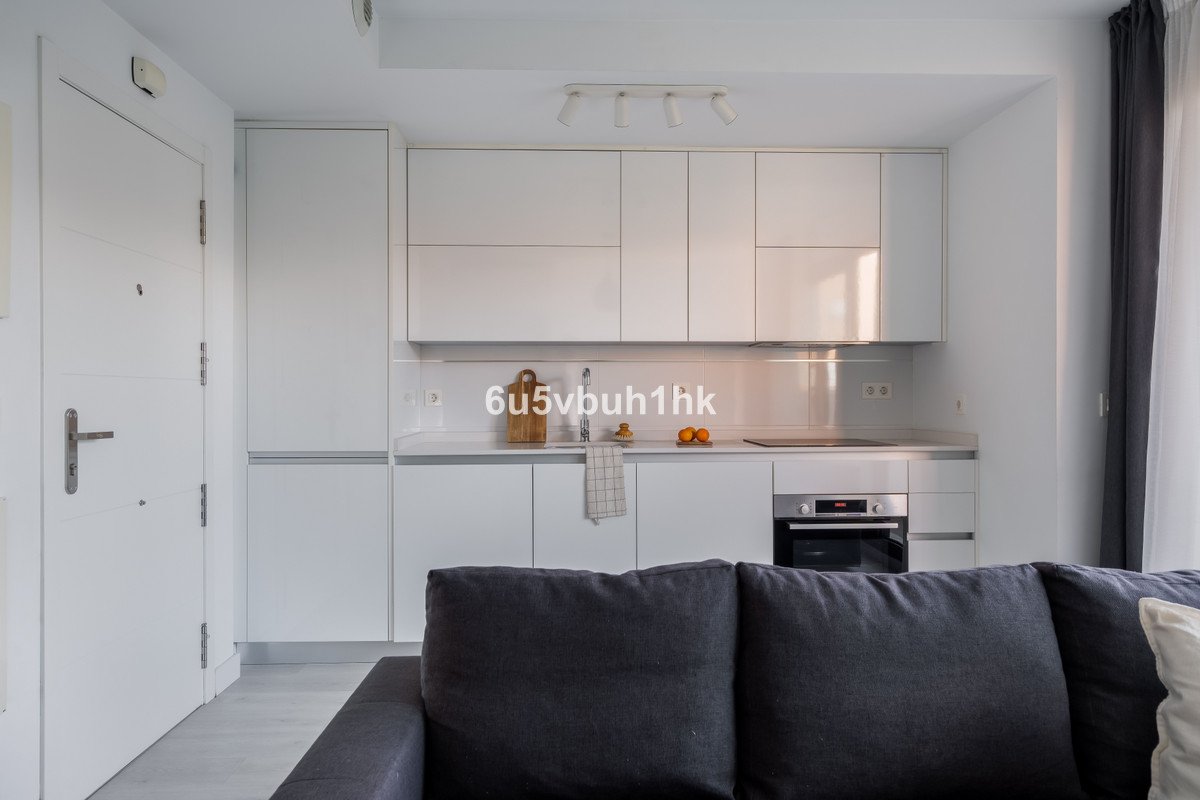 Modern kitchen with white cabinets and a dark sofa in living area