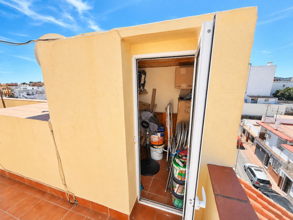 Small storage room with a fan and paint cans, accessed from a terrace with a town view.