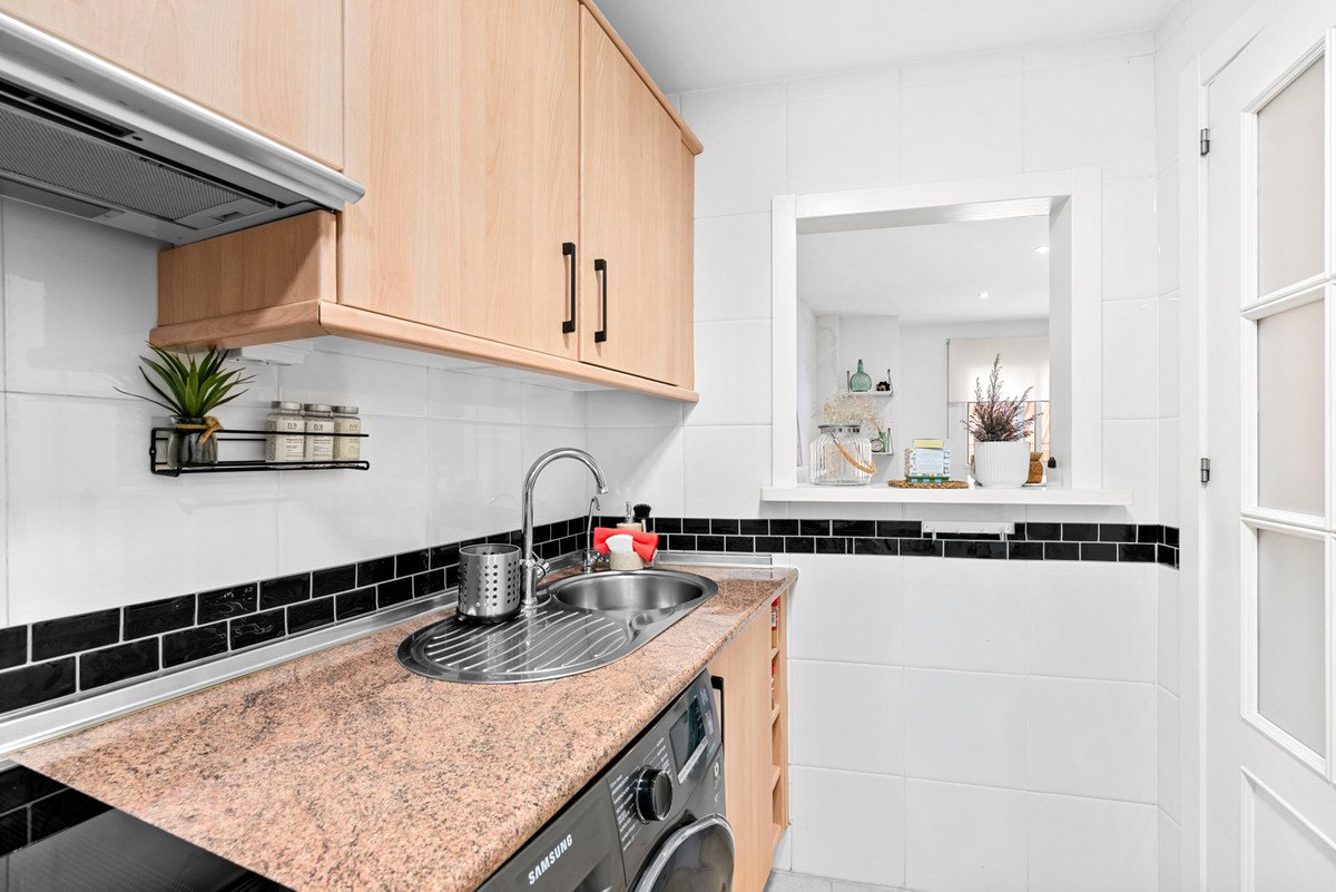 Modern kitchen with a stainless steel sink, granite countertop, light wood cabinets, and a pass-through window.