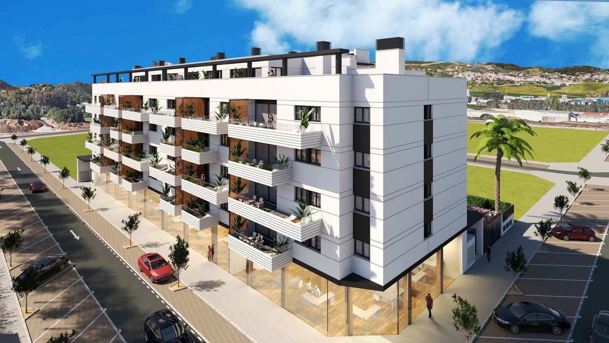 A modern apartment building with multiple floors, white balconies, and large windows, facing a street and green landscape.