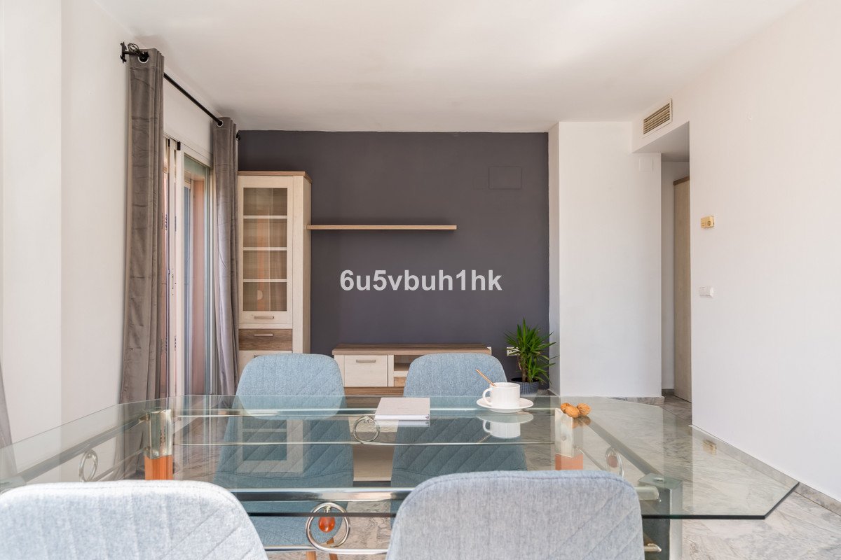 A living and dining area featuring a glass table, blue chairs, modern entertainment unit, and a plant.