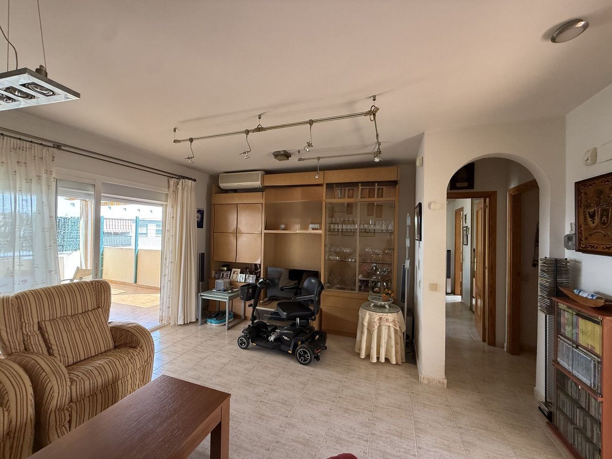 Living room with striped sofa, wheelchair, and balcony view through sliding doors