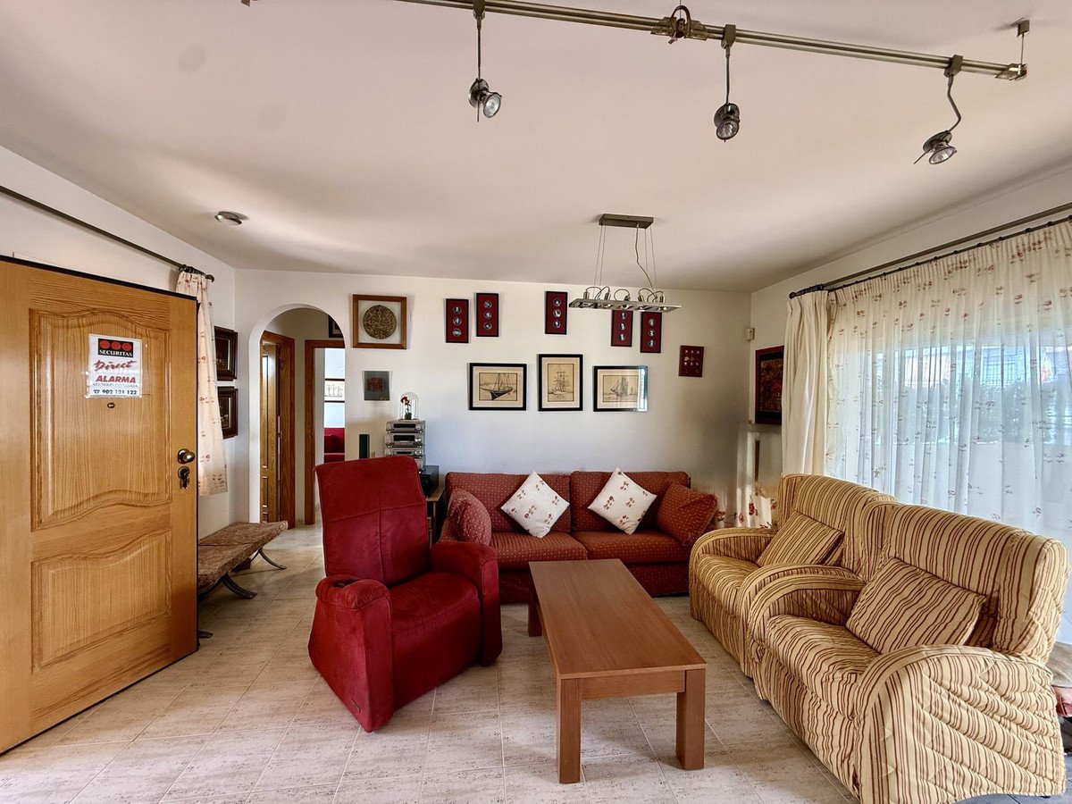 A living room with red and striped sofas, a coffee table, and a large window with curtains.