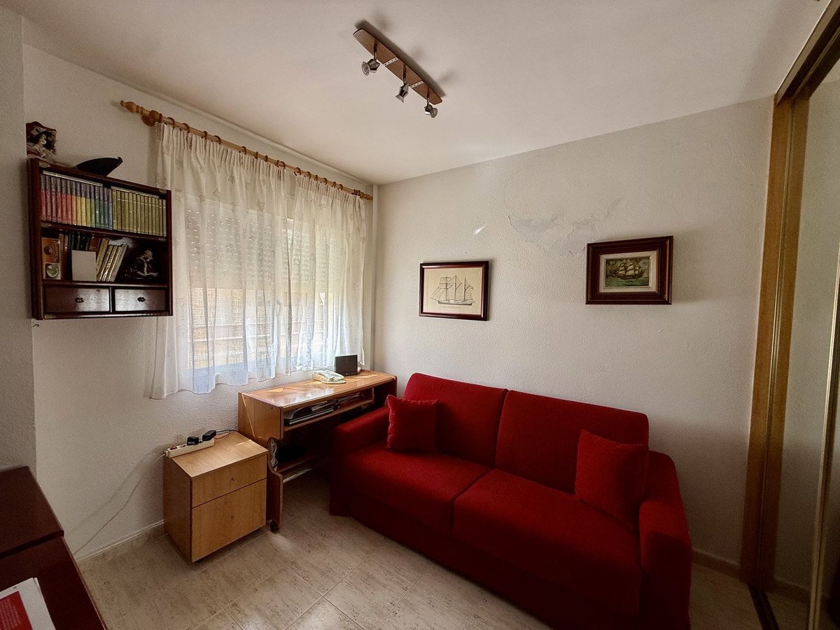Living room with red sofa, window with curtains, and wall art.