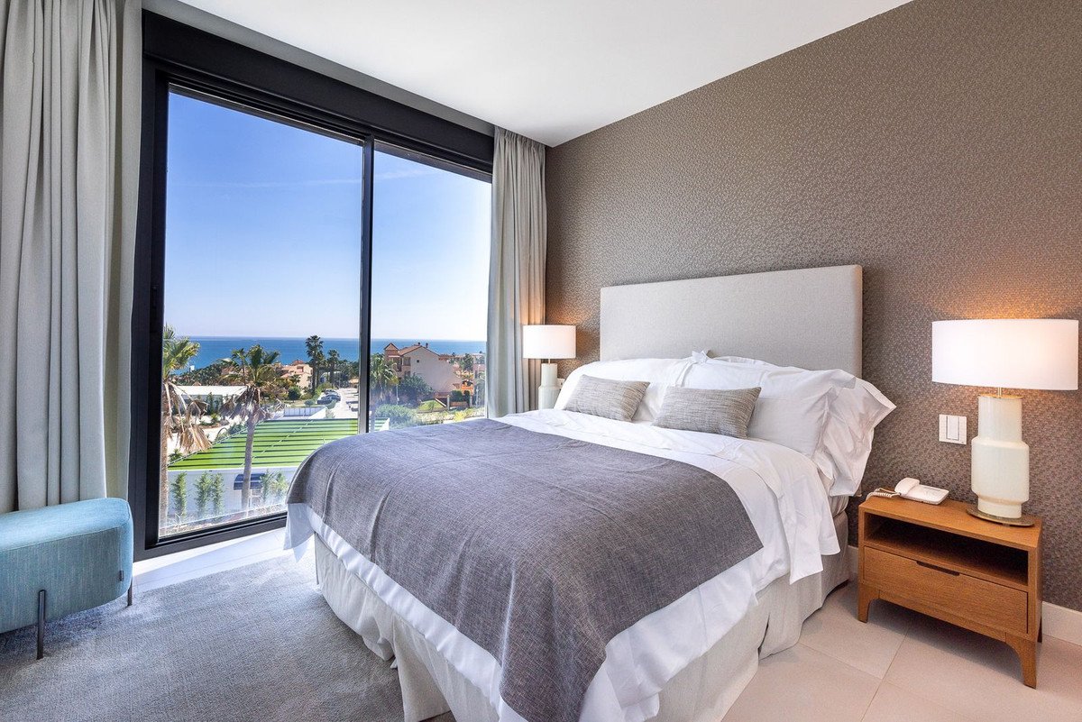 Bedroom with a large window offering a stunning sea view, modern decor, and a comfortable bed.