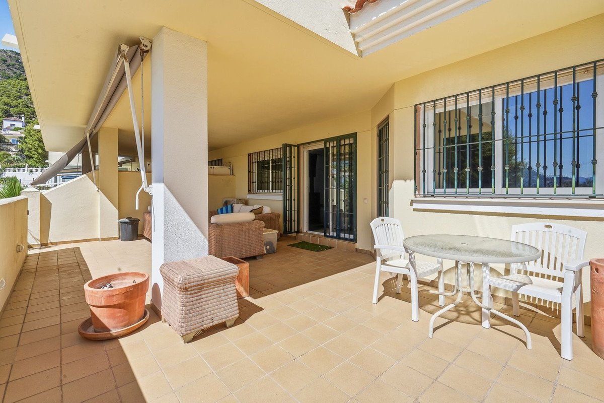 A spacious covered terrace with outdoor dining furniture and lounge seating, offering a pleasant outdoor living area.