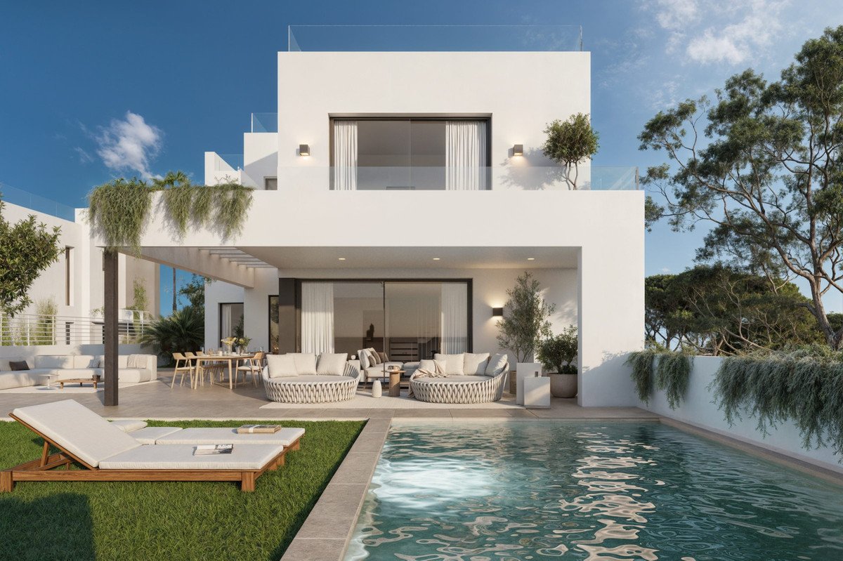 Modern villa exterior with a private pool, lounge seating, dining area, and lush greenery under a clear blue sky.