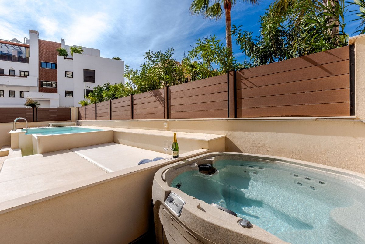 Outdoor jacuzzi and swimming pool on a sunny terrace with champagne and glasses. Luxury property feature.