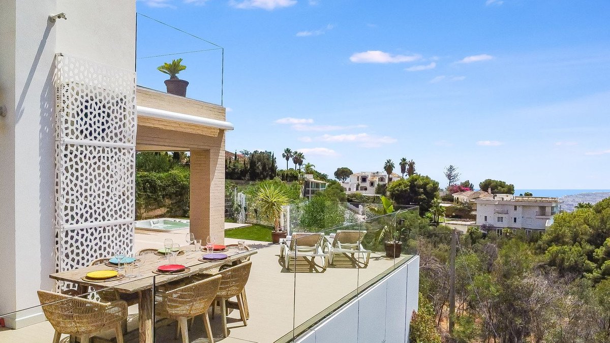 Spacious terrace with dining table, sun loungers, and a beautiful view of the sea and surrounding landscape.
