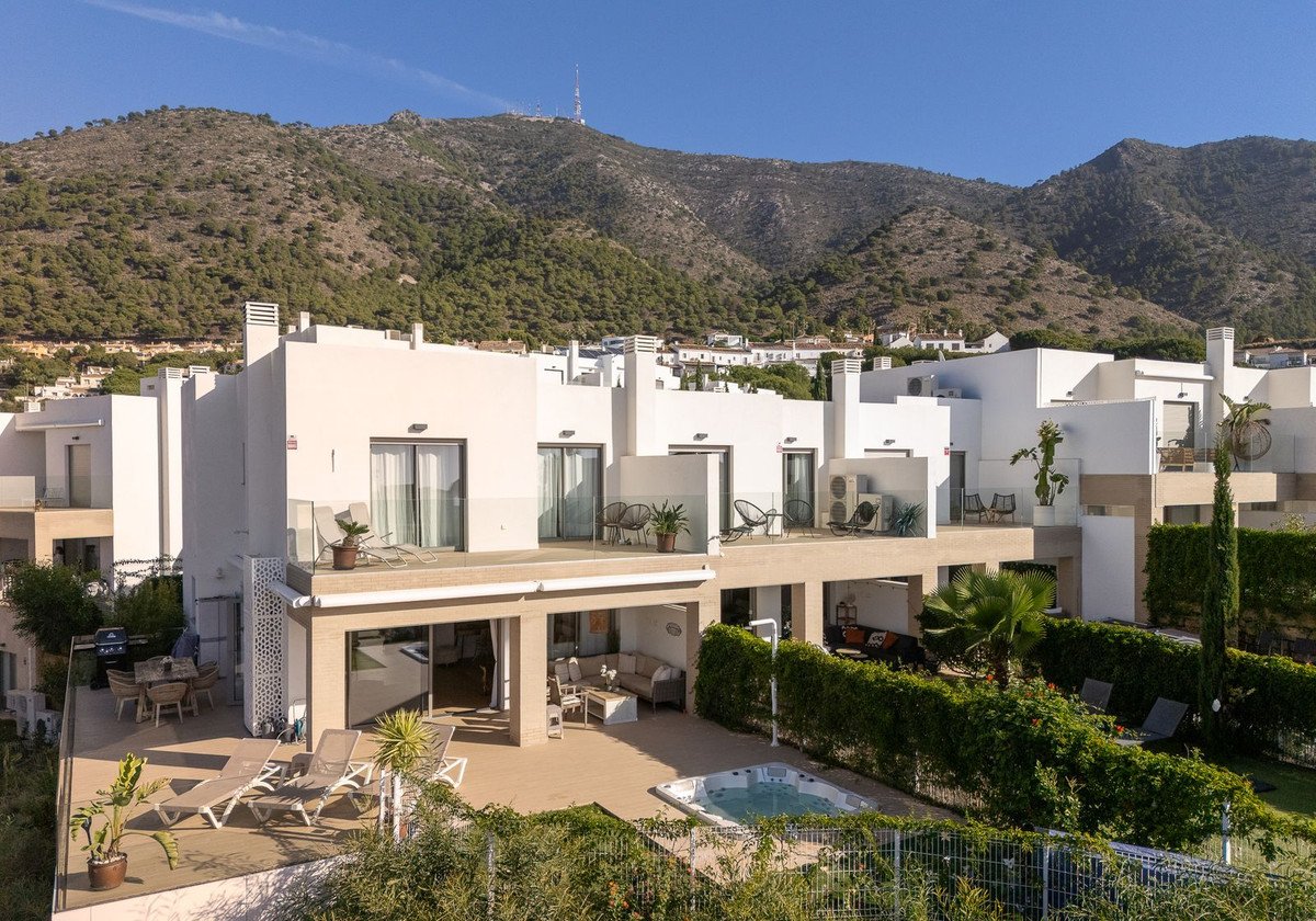 Modern townhouse with multi-level terraces, hot tub, outdoor seating, and a lush green garden with mountain views.