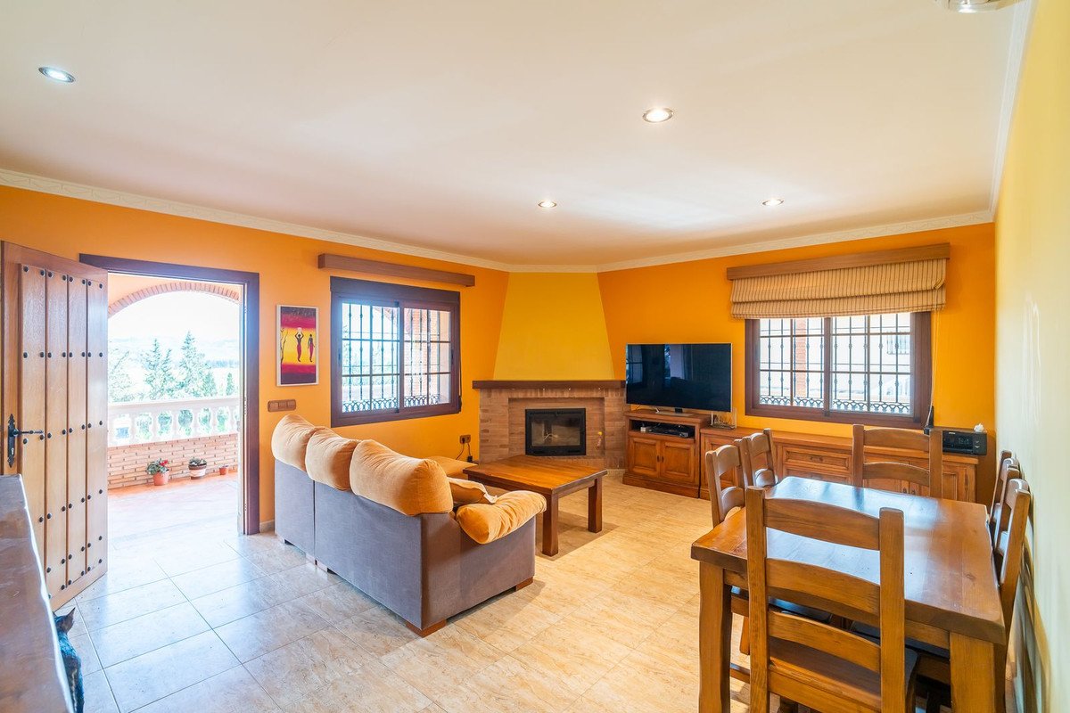 Living room with orange walls, fireplace, sofa, dining table, and terrace view