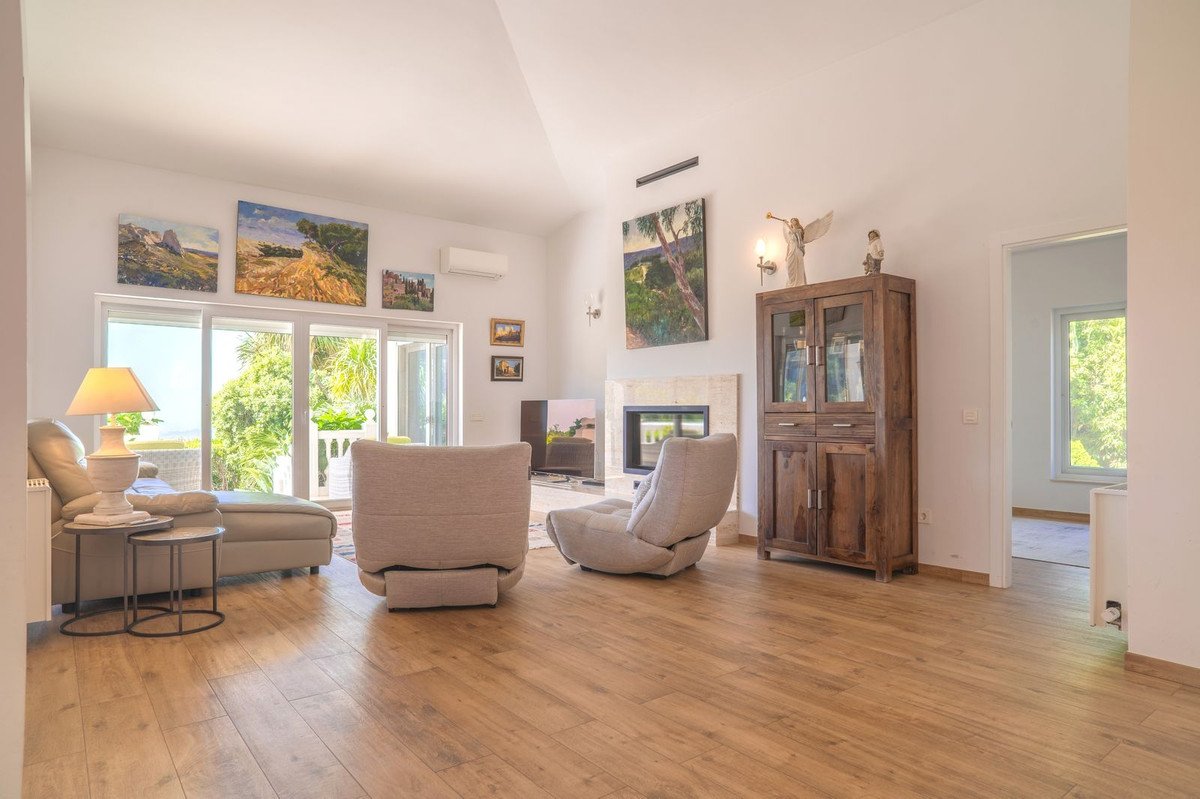 Spacious living room with wooden floors, large windows, fireplace, and artwork.