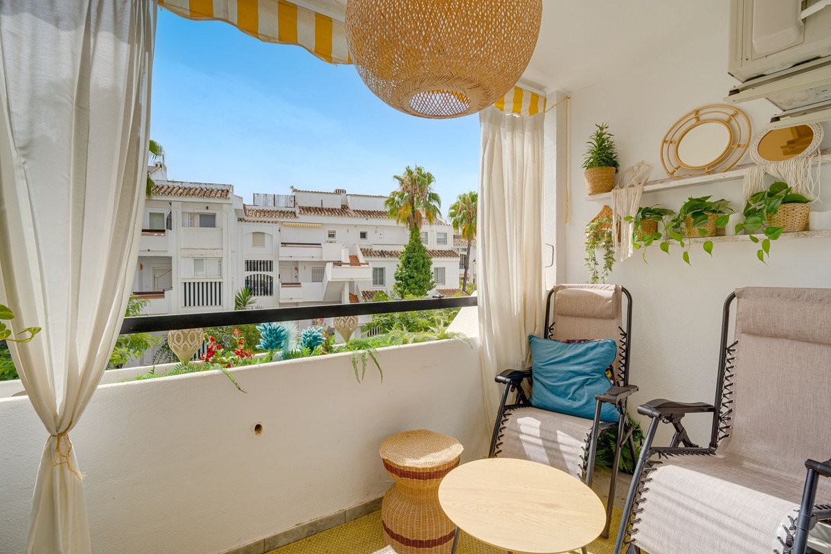 Balcony with lounge chairs, plants, and view of white buildings